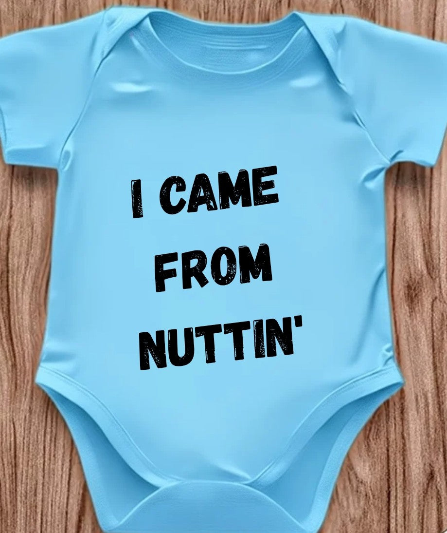Funny baby onesie with the text 'I Came From Nuttin' on a wooden background