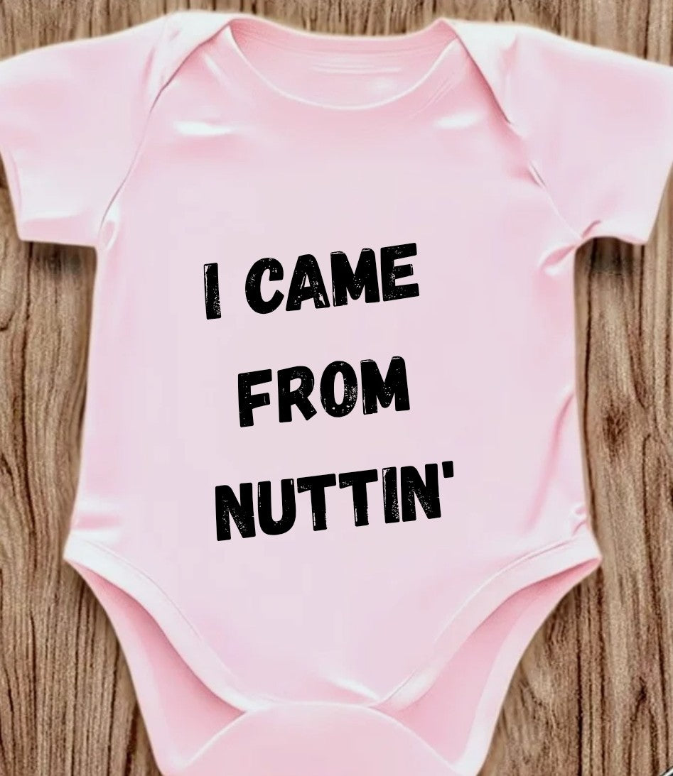 Funny baby onesie with the text 'I Came From Nuttin' on a wooden background